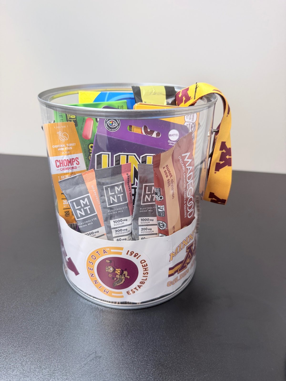 Minnesota Golden Gophers college care package bucket filled with snacks, electrolyte drink mixes, and games