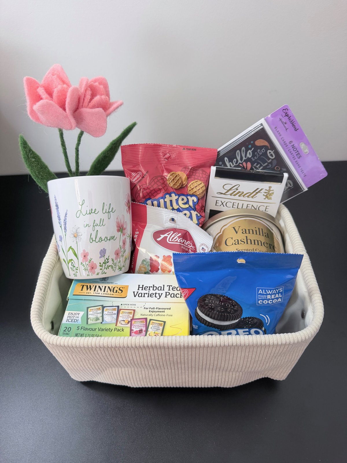 Essential Collection gift basket with a wildflower mug, felt tulip, herbal tea variety pack, candle, and sweet treats